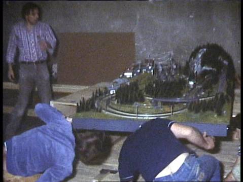 Vereinsmitglieder arbeiten in der alten Feuerwehrhalle am Aufbau einer Modellbahnanlage mit Gleisen, Bergen und Landschaftsgestaltung.