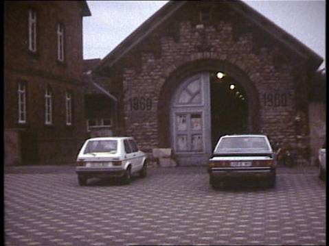 Historische Außenaufnahme der alten Feuerwache in Gernsheim mit ihrem großen Rundbogentor. Vor dem Gebäude stehen zwei Autos.