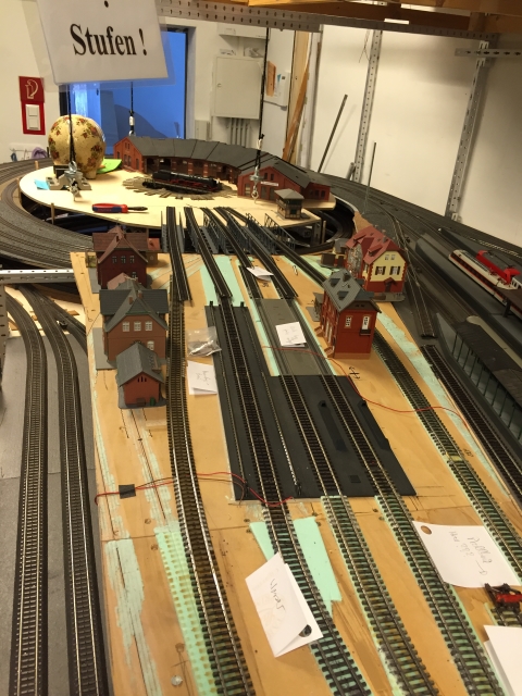 Übersicht des im Bau befindlichen Bahnbetriebswerks mit zahlreichen Zufahrts- und Abstellgleisen, Modellgebäuden sowie Drehscheibe und Ringlokschuppen im Hintergrund.