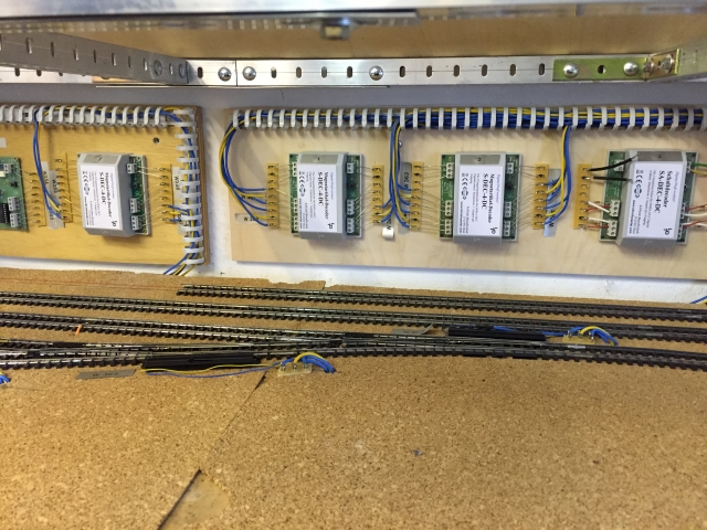 Parallel verlaufende Modellbahngleise des Schattenbahnhofs 3xx mit Weichen und sichtbaren Kabelanschlüssen, darüber mehrere verdrahtete Elektronikmodule.