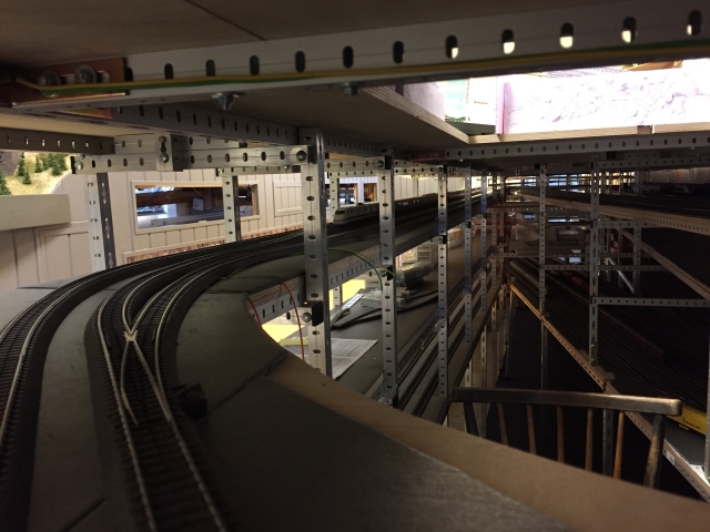 Gebogene Modellbahngleise mit Weiche führen von der unteren Paradestrecke in den mehrstöckigen Schattenbahnhof.