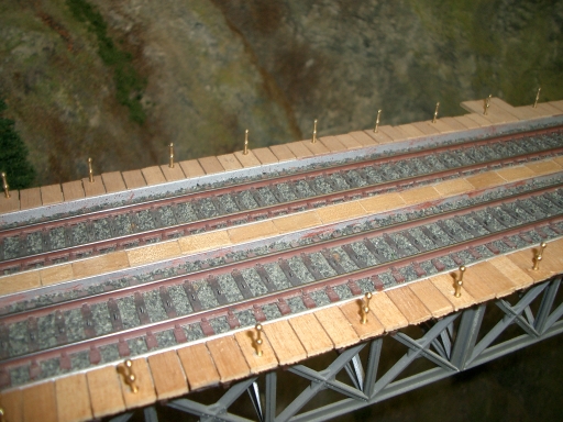 Zweigleisige Modellbahnbrücke mit Holzbohlen, zahlreichen Geländerpfosten und grauem Stahlfachwerk