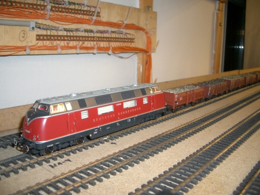 Rot-beige Diesellokomotive vor einem langen Güterzug mit braunen offenen Wagen gefüllt mit Rüben