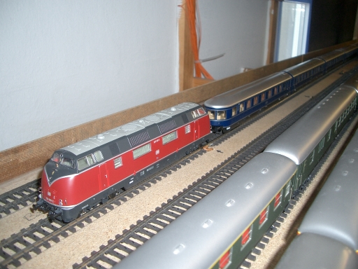 Rot-beige Diesellokomotive neben einem blau-silbernen historischen Reisezug