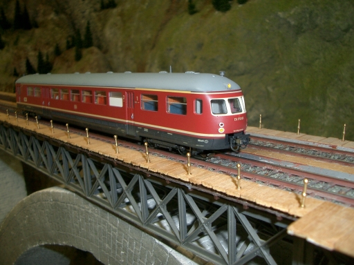 Roter Akku-Triebwagen ETA 176 auf einer zweigleisigen Stahlfachwerkbrücke der Modellbahnanlage