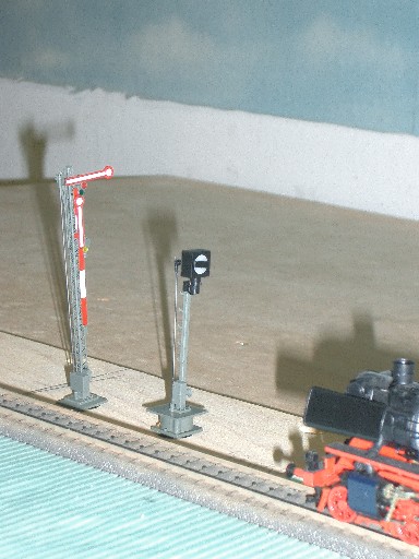 Zwei Modellbahn-Signale neben einem Gleis, darunter ein rot-weißes Formsignal mit waagerechtem Signalflügel