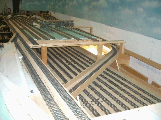 Blick auf die Gleisanlagen des Hauptbahnhofs während der Bauarbeiten. Mehrere parallel verlaufende Gleise liegen auf unterschiedlich hohen Holzmodulen, teilweise mit Oberleitungsmasten.