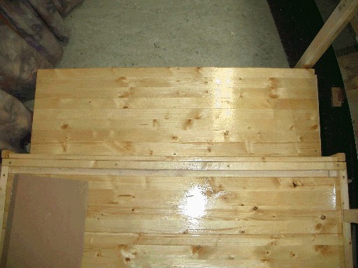 Nahaufnahme der glänzend lackierten Holzbretter des Besucherpodests von oben. Am Rand ist eine Lücke zwischen den Brettern und der Begrenzung zu erkennen.