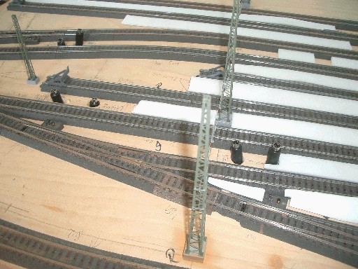 Blick auf ein noch nicht ausgestaltetes Bahnhofsmodul mit mehreren Gleisen, Oberleitungsmasten und vorbereiteten Anschlüssen für Signale