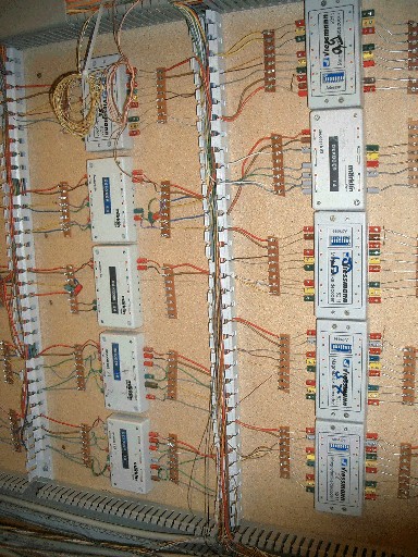 Mehrere Schaltdecoder und Anschlussklemmen auf einer Montageplatte, verbunden durch farbige Leitungen und Kabelkanäle.