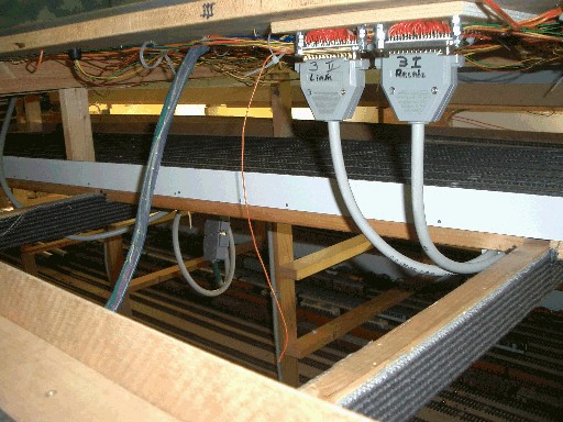 Unterseite eines Modellbahnmoduls mit gebündelten Kabeln, zwei beschrifteten Steckverbindungen und Kabelspiralen