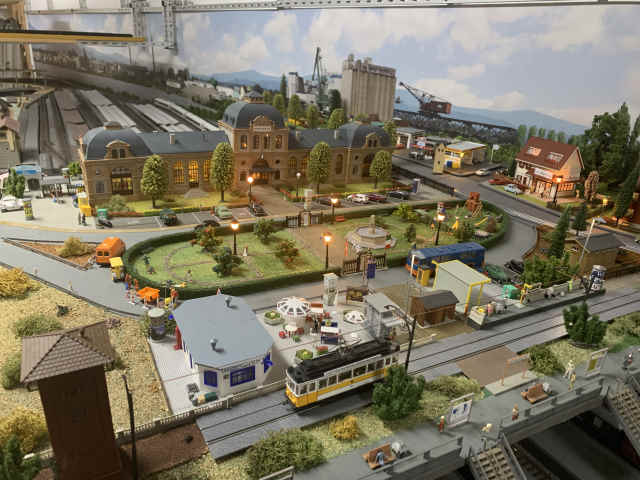 Bahnhofsvorplatz mit Parkanlage, Spielplatz und historischer Straßenbahn im Vordergrund