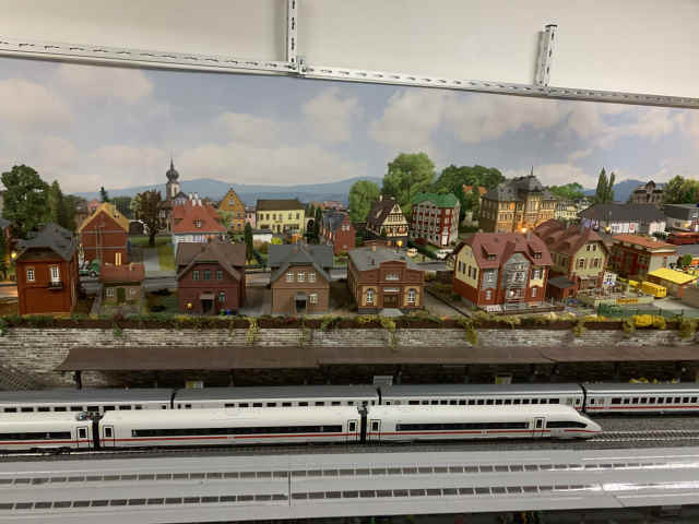 Verschiedene Gebäude oberhalb des Bahnhofs. Im Bahnhof stehen zwei Züge am Gleis.