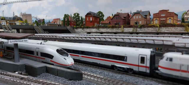 ICE und Intercity mit weißer Elektrolokomotive der Baureihe 103 an den Bahnsteigen des Modellbahnhofs Schöfferstadt Hbf.