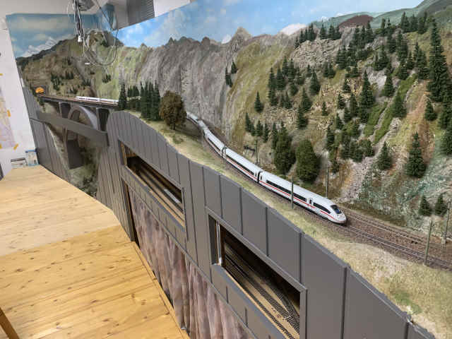 Zwei ICE-Züge auf der mehrgleisigen Paradestrecke der Modellbahnanlage, mit Felslandschaft, Brücke und Tunnelportal.