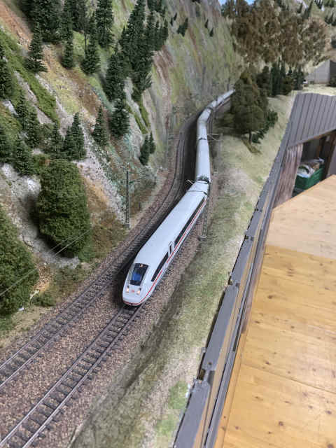 ICE 4 auf der Paradestrecke des MEC Gernsheim in einer Kurve durch eine felsige, bewaldete Gebirgslandschaft, kurz vor dem Löschberg-Basistunnel.
