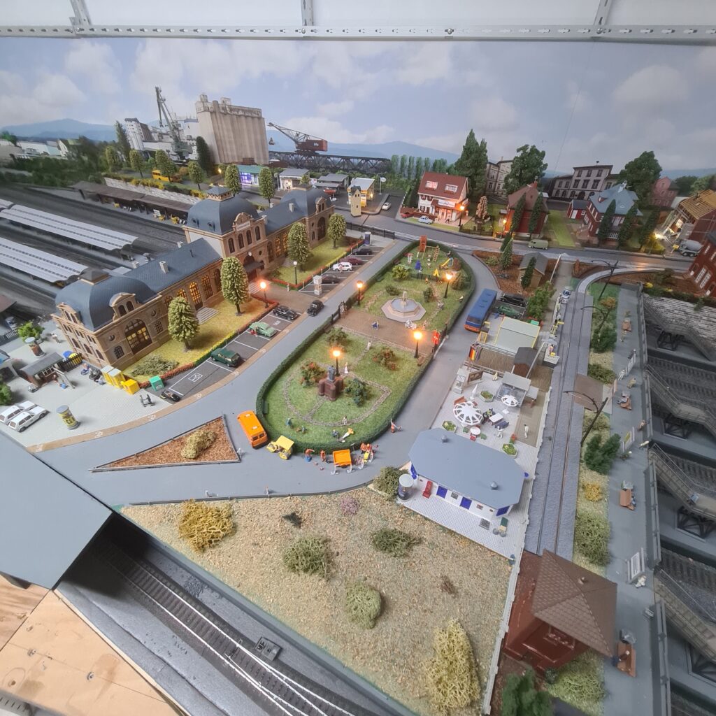 Blick über den beleuchteten Bahnhof und die angrenzende Stadtlandschaft der Modellbahnanlage.