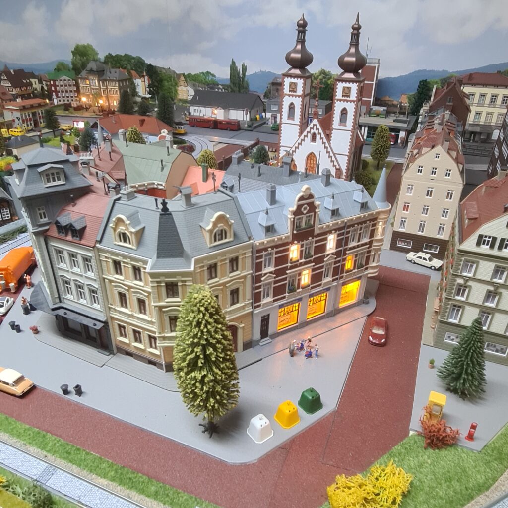 Modellstadt mit beleuchteten Häusern, Straßen und einer Kirche mit zwei Türmen.