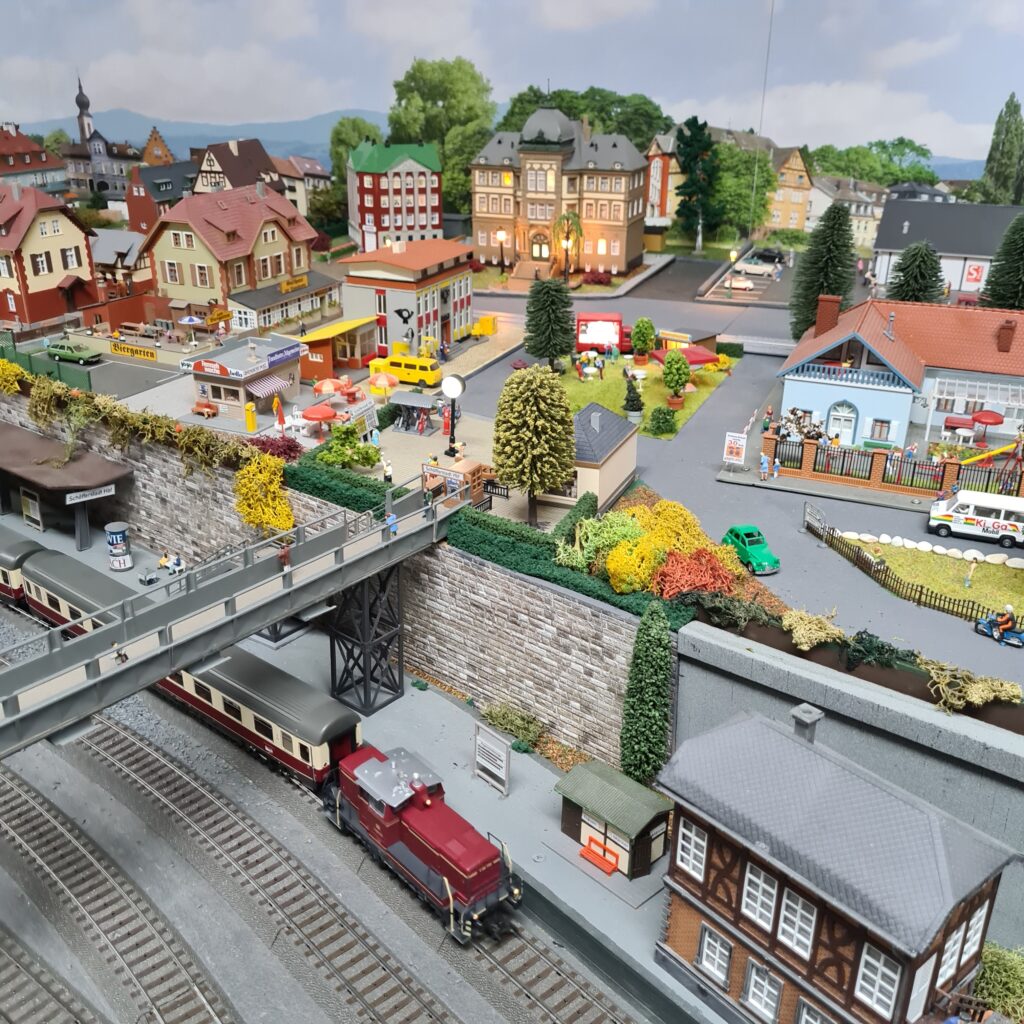 Blick auf die Modellstadt mit Straßen, Gebäuden und einer Brücke über mehrere Bahngleise.