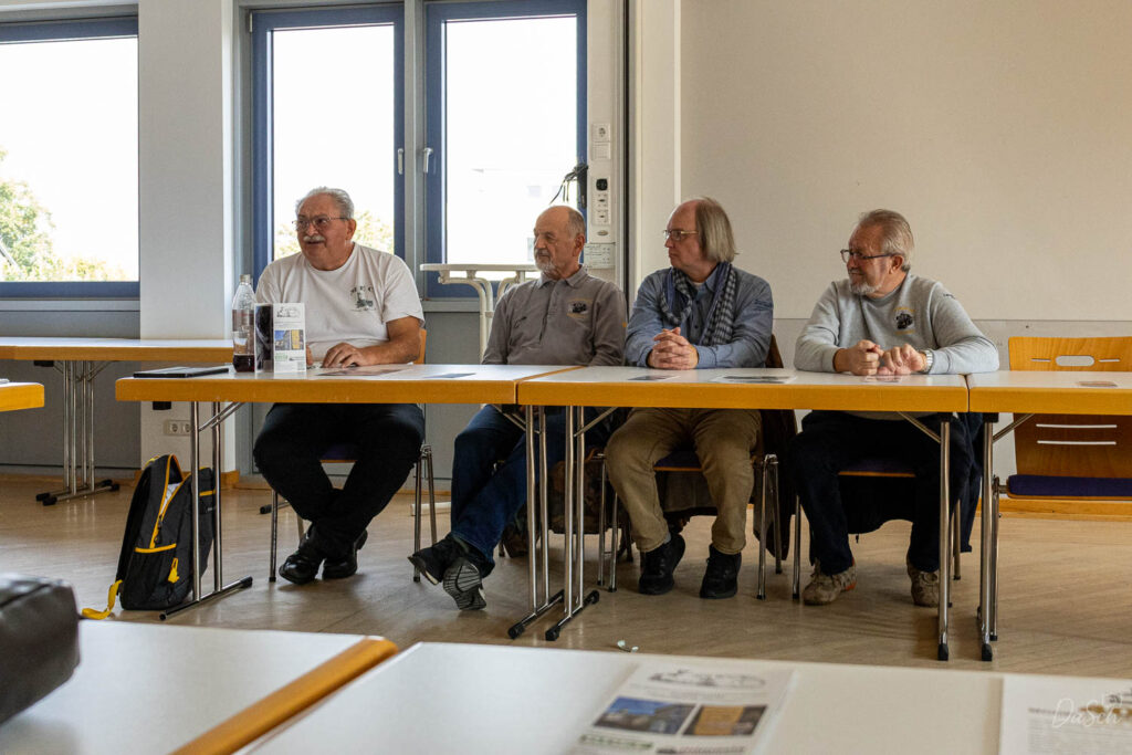 Vier Teilnehmer sitzen während des offiziellen Teils des BDEF-Regionaltreffens nebeneinander an Konferenztischen.
