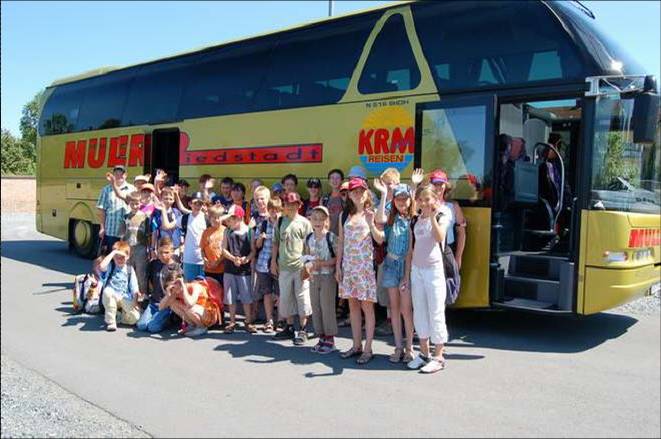 Gruppe von Kindern und Betreuern vor einem Reisebus während eines Ausflugs der Ferienspiele.