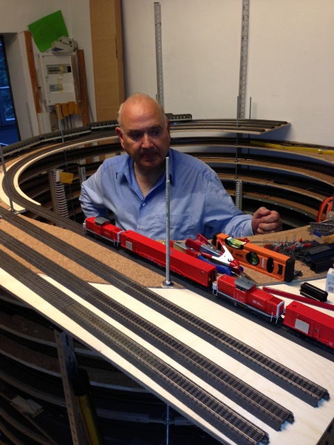 Volker begutachtet den roten Tunnelrettungszug auf der Teststrecke vor dem mehrstöckigen Gleiswendel.