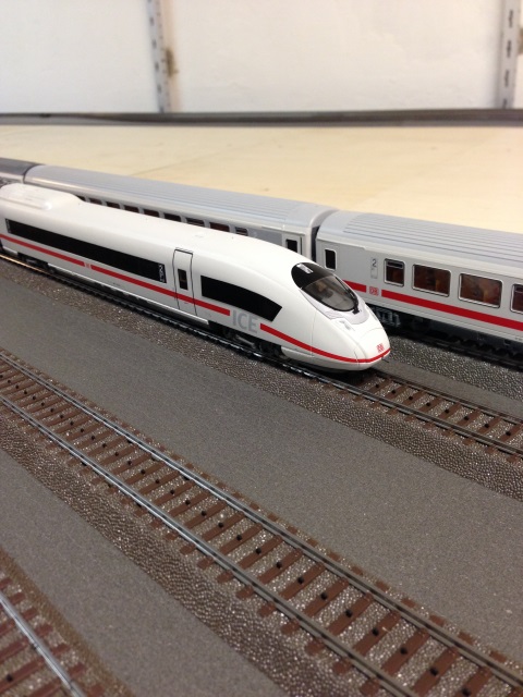 Weißer ICE-Hochgeschwindigkeitszug neben einem weiteren ICE auf parallelen Modellbahngleisen