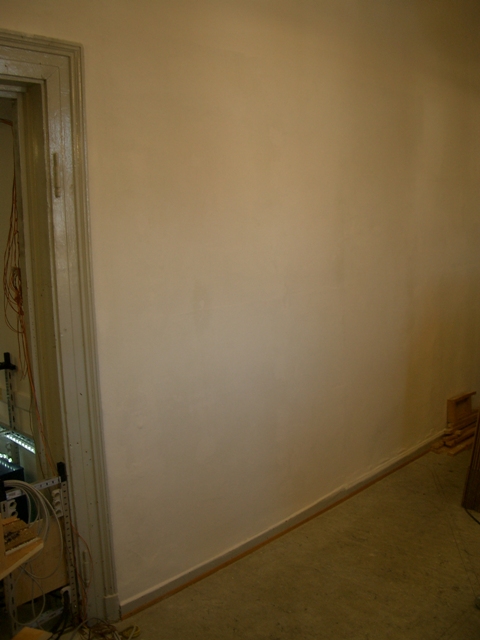 Leere, weiß gestrichene Wand im Vereinsraum neben einem Türrahmen