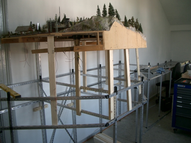 Seitliche Ansicht des erhöhten Landschaftsmoduls mit Felsen, Nadelbäumen und sichtbarem Holzunterbau