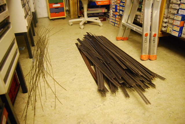 Abgebaute Modellbahngleise liegen gebündelt auf dem Boden eines Clubraums.