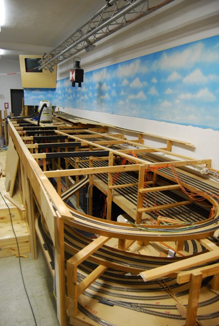 Teilweise zurückgebaute Modellbahnanlage mit offenen Holzrahmen und verbliebenen Gleisen auf mehreren Ebenen.