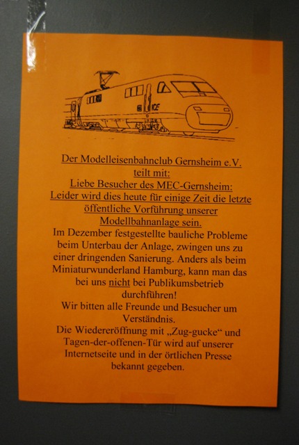 Orangefarbener Aushang des MEC Gernsheim zur vorübergehenden Schließung der Modellbahnanlage wegen notwendiger Sanierungsarbeiten.