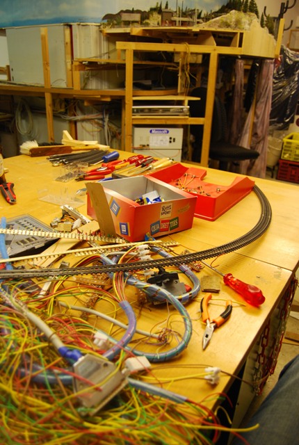 Arbeitsfläche mit Werkzeugen, Kabeln und ausgebauten Gleisteilen während des Rückbaus der Modellbahnanlage.