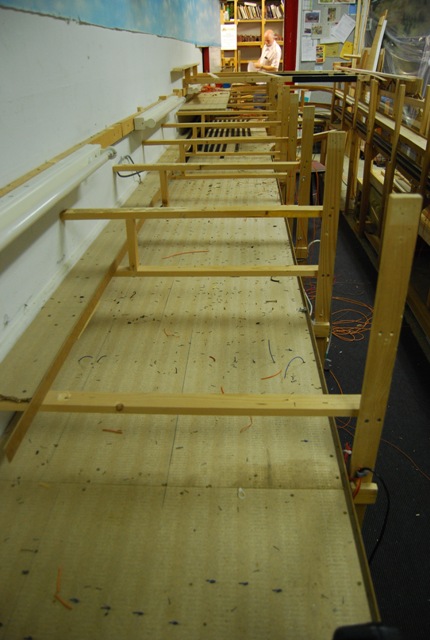 Blick entlang der freigelegten Holzrahmen und Grundplatten der Modellbahnanlage.